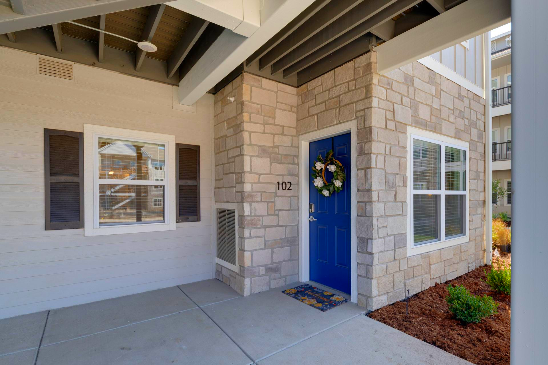 Exterior of a building with a blue door, stone accents, and a welcome mat.