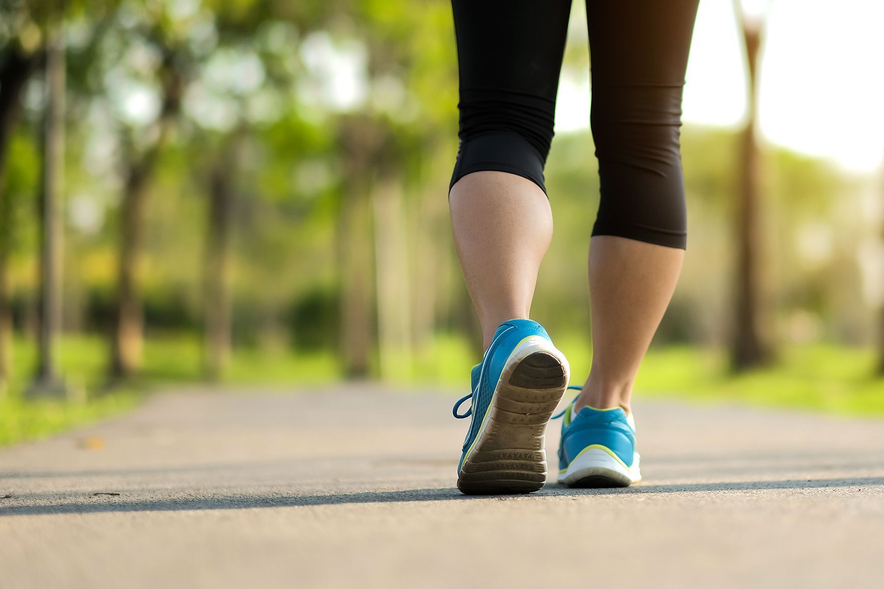 A woman is walking down a path in a park.