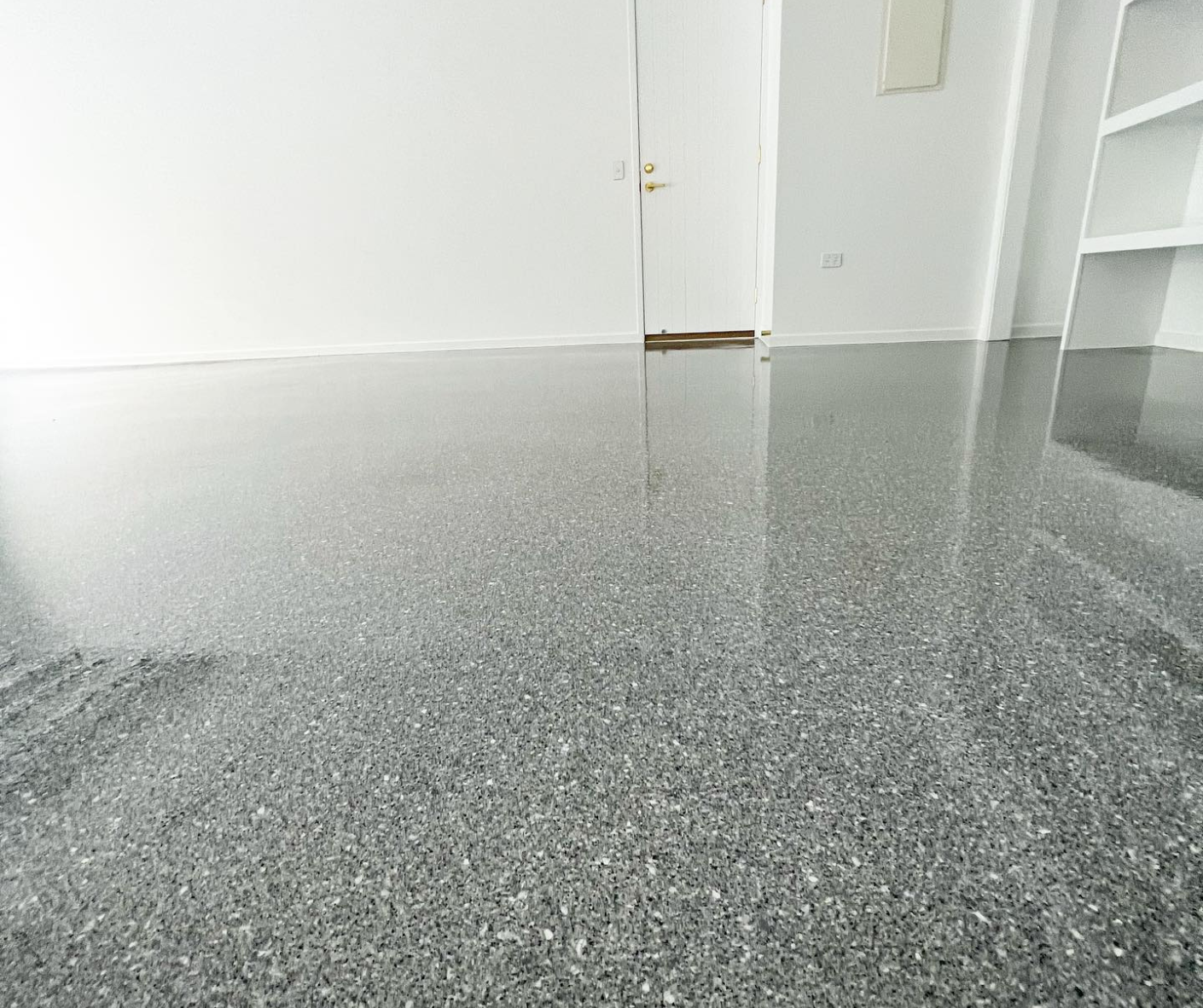 Empty room with gray speckled floor and white walls, viewed from a low angle. Empty room with gray speckled floor and white walls, viewed from a low angle.