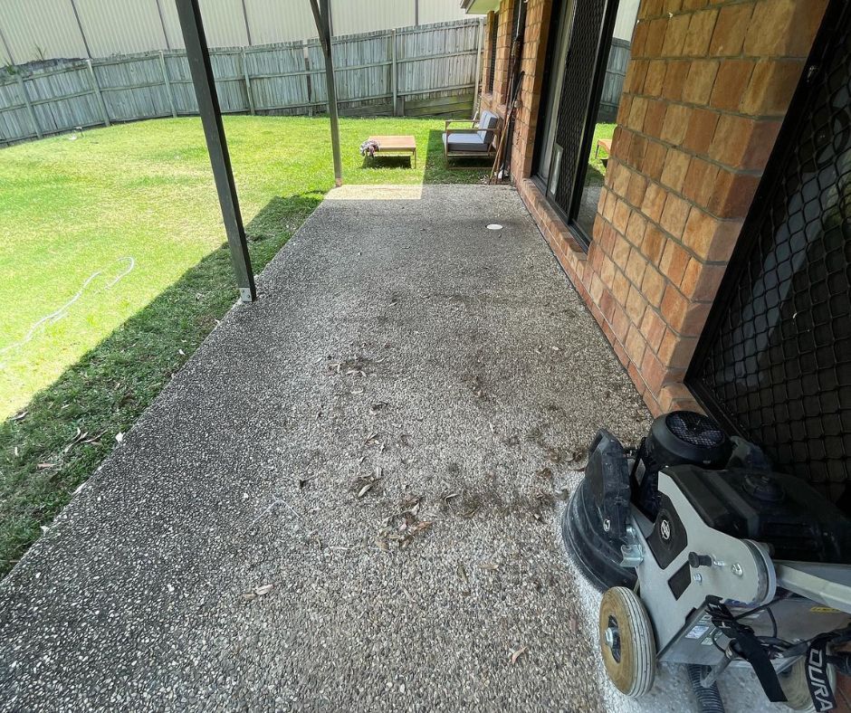 A view of a concrete patio with a floor sanding machine preparing it for an exposed aggregate finish.