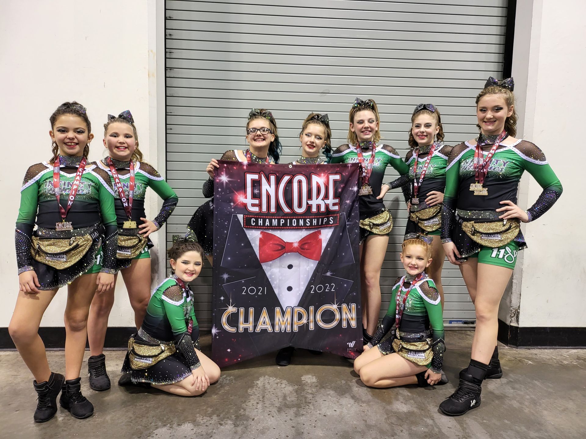 A group of cheerleaders are posing for a picture with a banner that says encore champion.