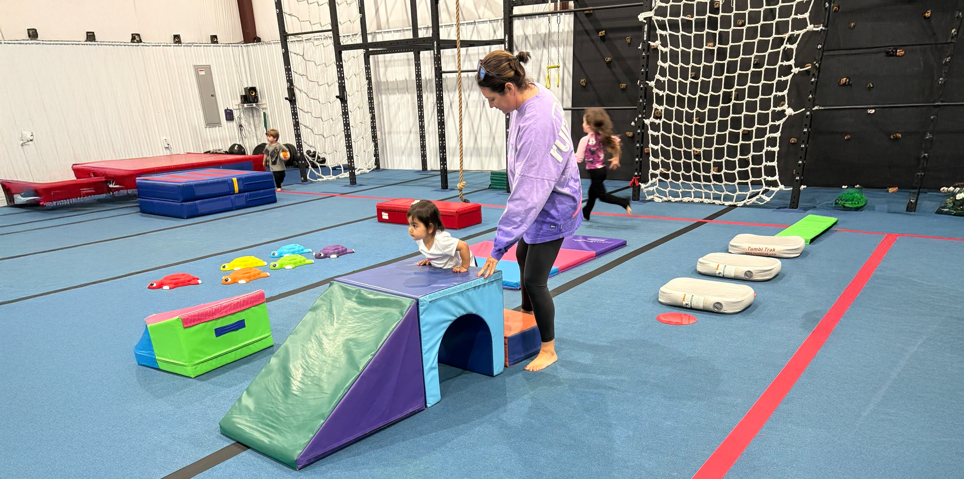 A woman is playing with a child in a gym.
