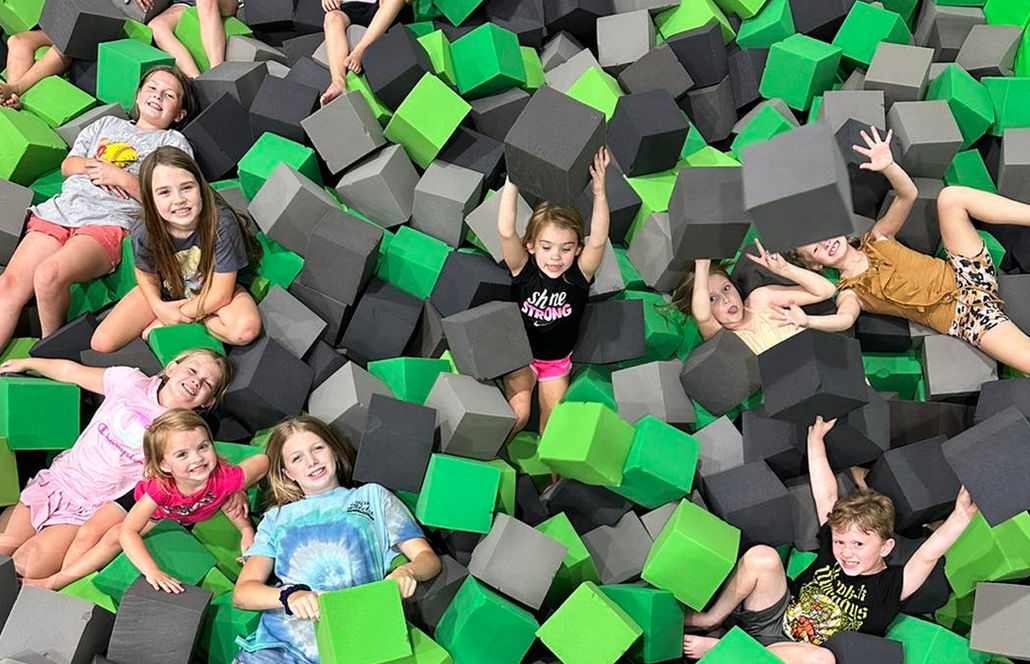 A group of children are laying in a pile of foam cubes.