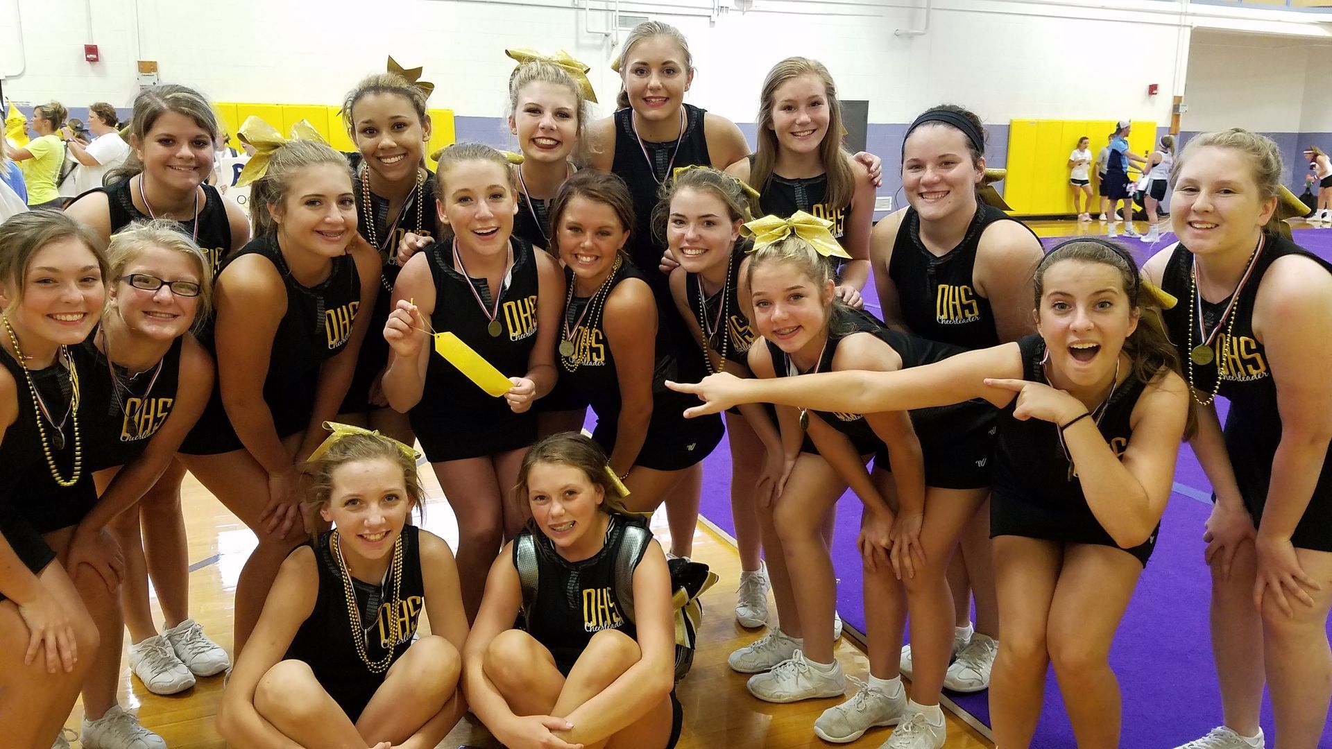 A group of cheerleaders are posing for a picture in a gym.