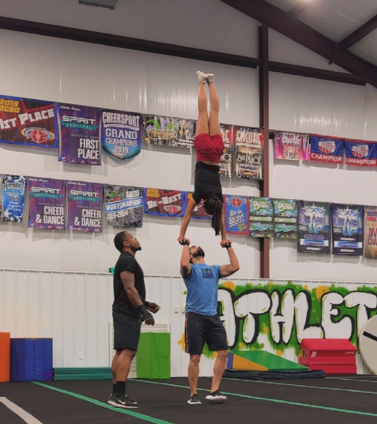 A cheerleader is doing a handstand in front of a sign that says athlete