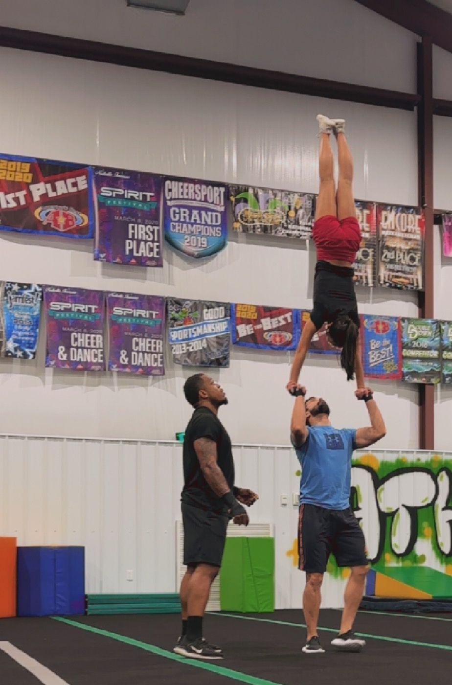 A cheerleader is doing a handstand in front of a sign that says athlete