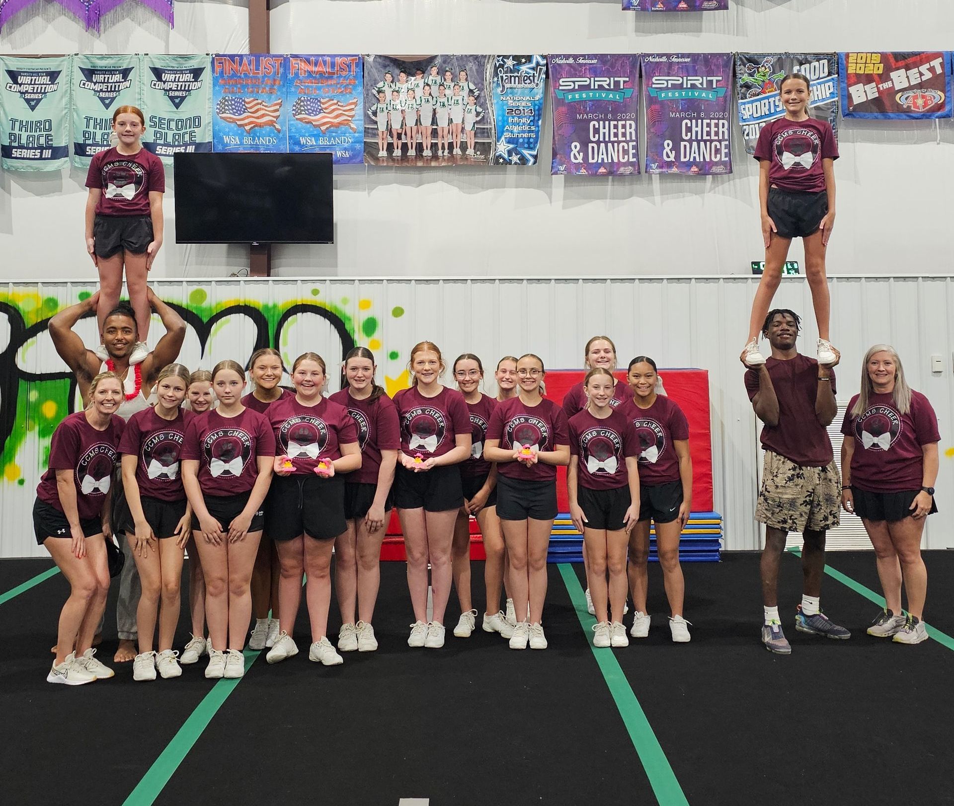 A group of cheerleaders are posing for a picture in a gym.