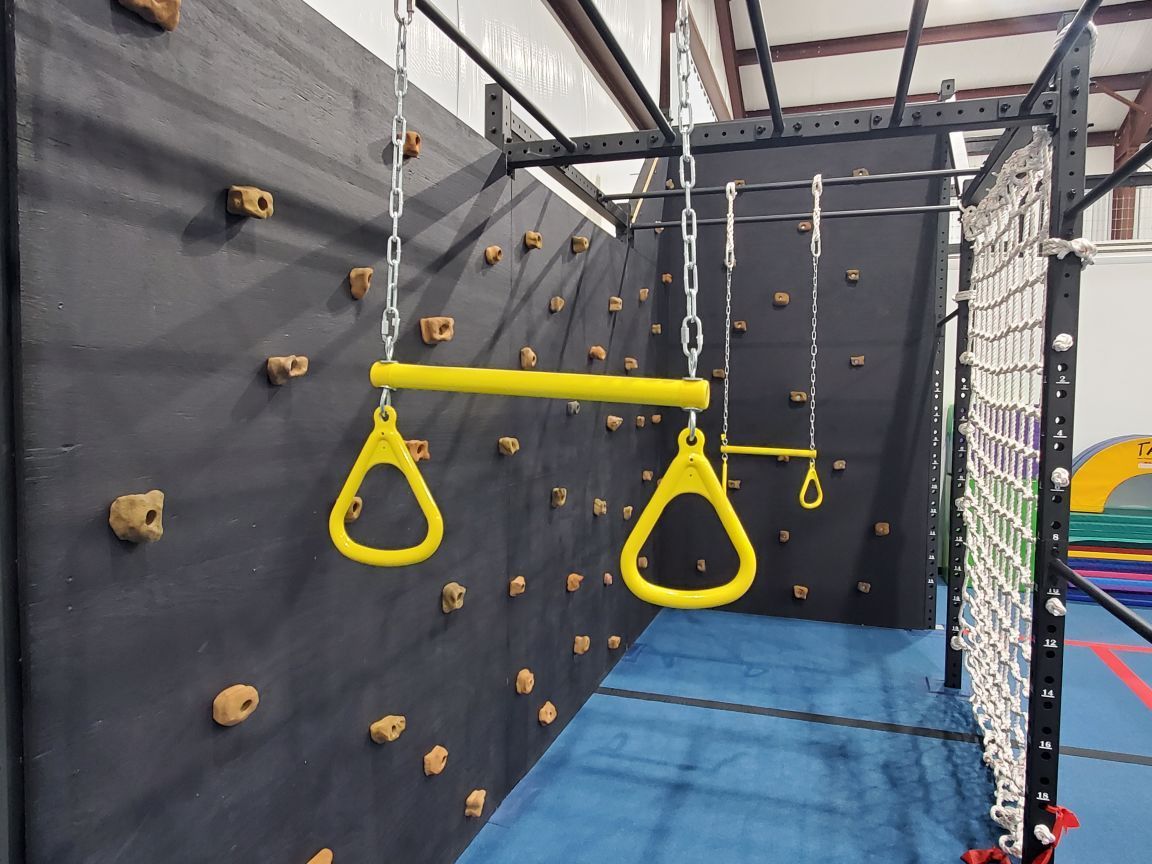 A climbing wall with yellow rings hanging from chains