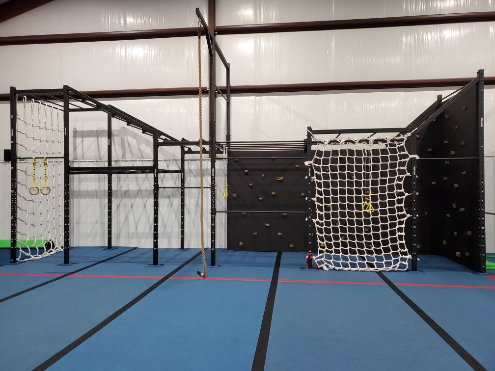 A gym with a ropes course and a climbing wall