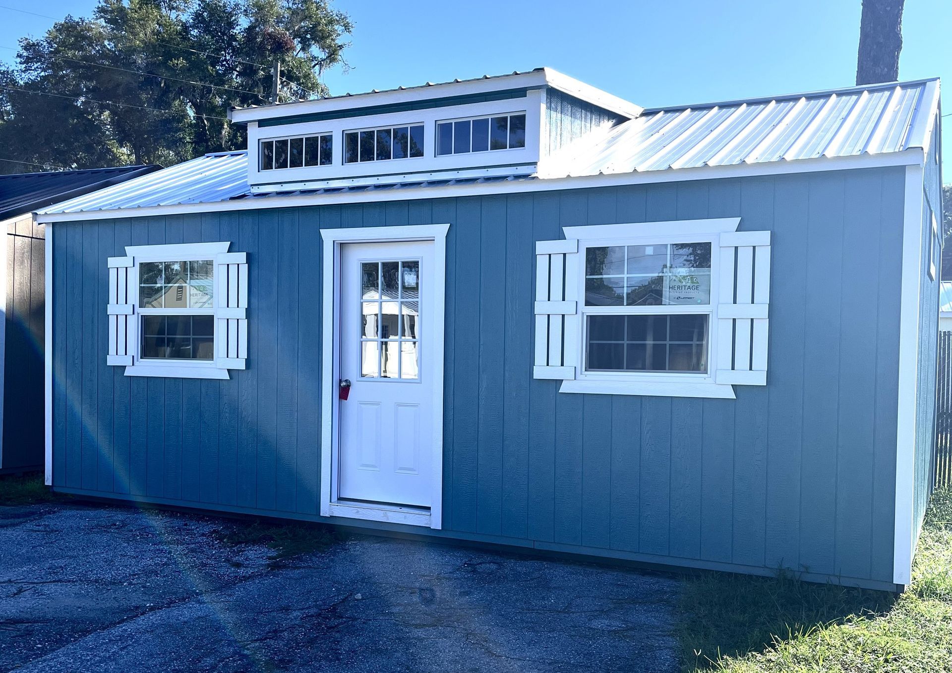 Black shipping container building with rooftop deck and adjacent small dome structure, in a landscaped outdoor setting. Black shipping container building with rooftop deck and adjacent small dome structure, in a landscaped outdoor setting.
