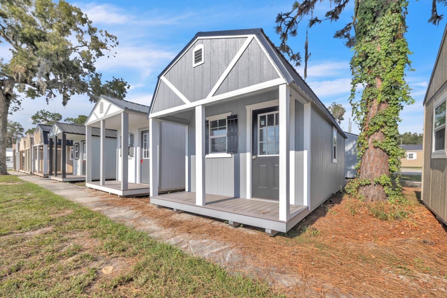 Tiny gray cabins with porches lined up outside, under a blue sky.