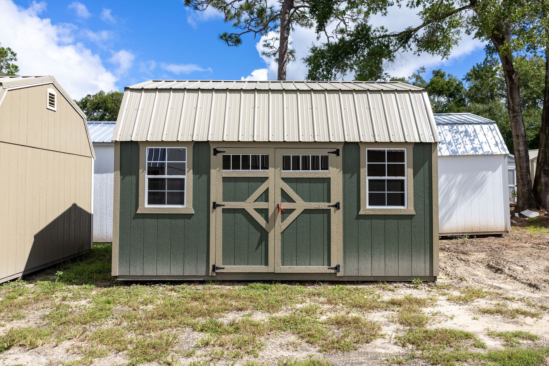 Light gray shed with teal doors and windows, set against trees.