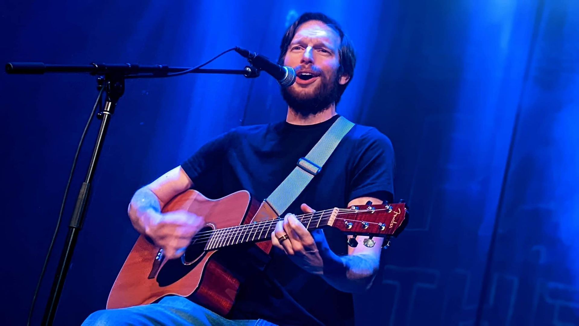 A group of people are standing on a stage in front of a bud light sign.