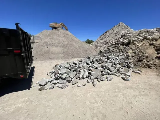 A dump truck is parked next to a pile of rocks