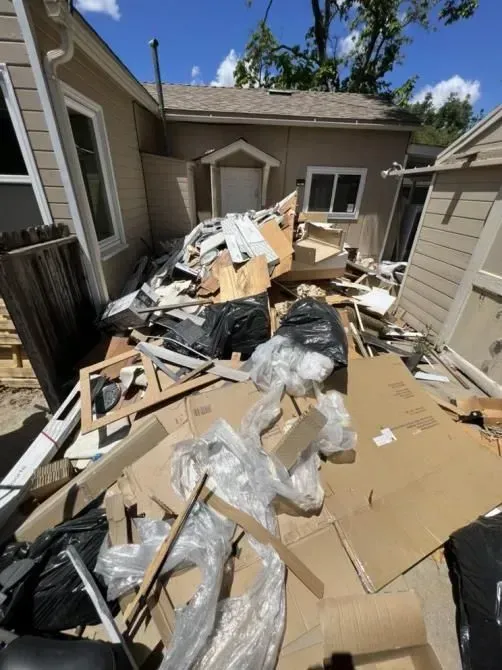 A pile of cardboard boxes is sitting in front of a house.