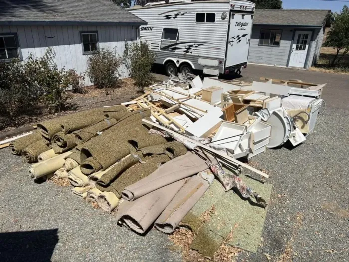 A trailer is parked in front of a pile of junk