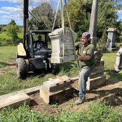 a man is lifting a gravestone with a forklift in a cemetery .