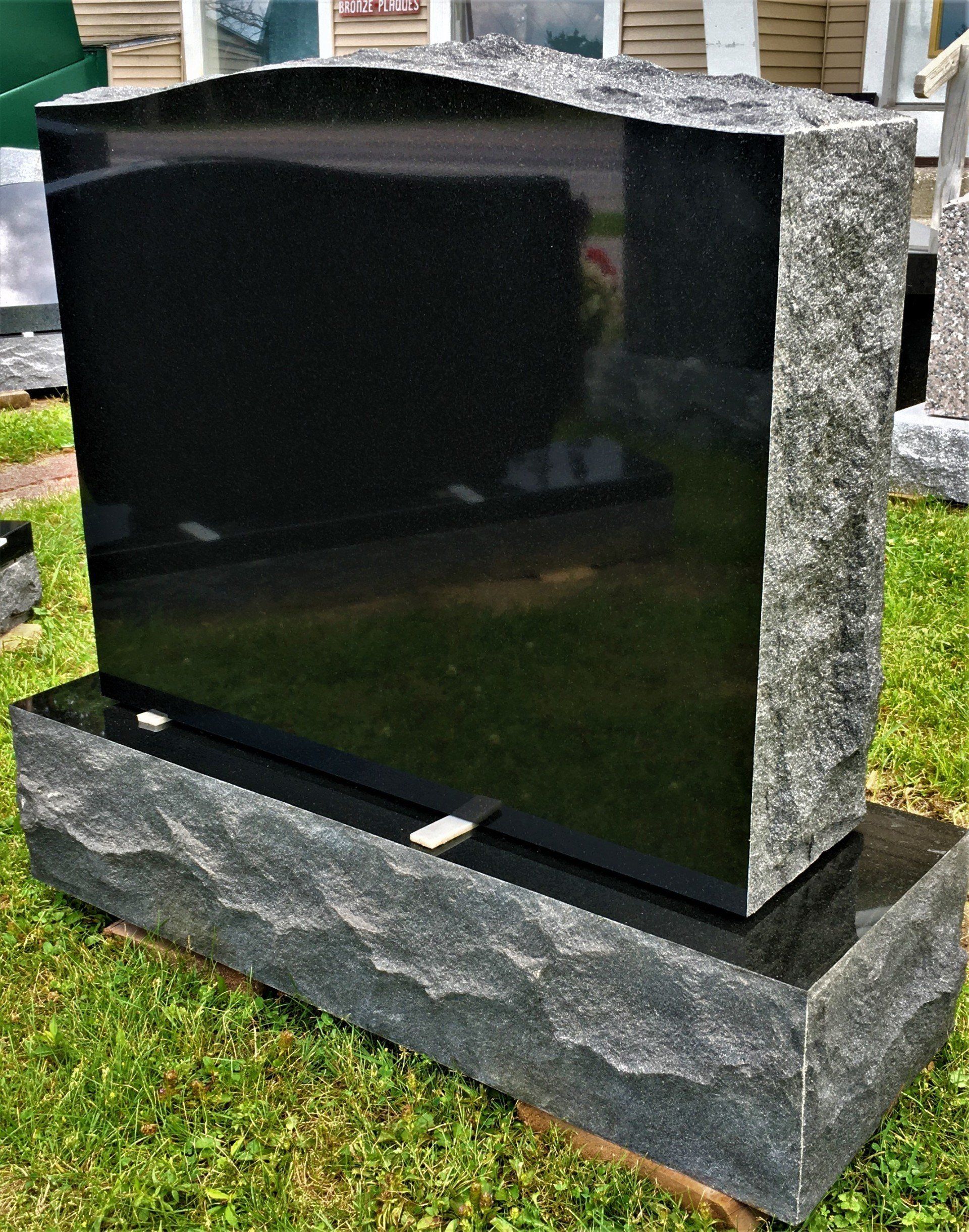 a black gravestone is sitting in the Champlain Monuments display