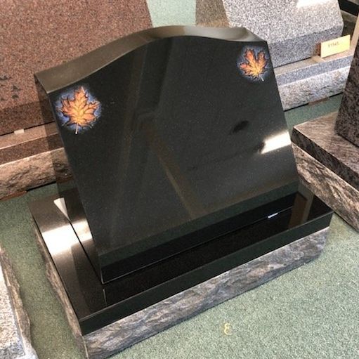 a black gravestone with a maple leaf on it is sitting in the champlain monuments display
