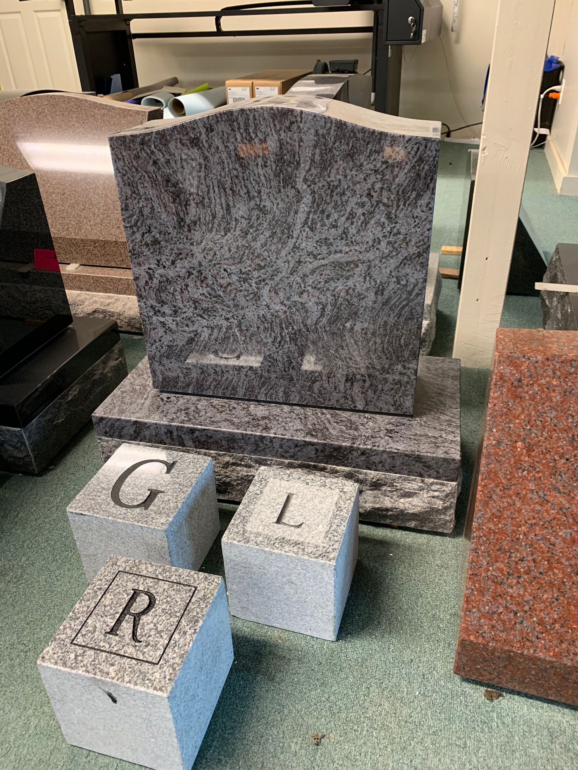 A gravestone is sitting on top of a stack of granite blocks.