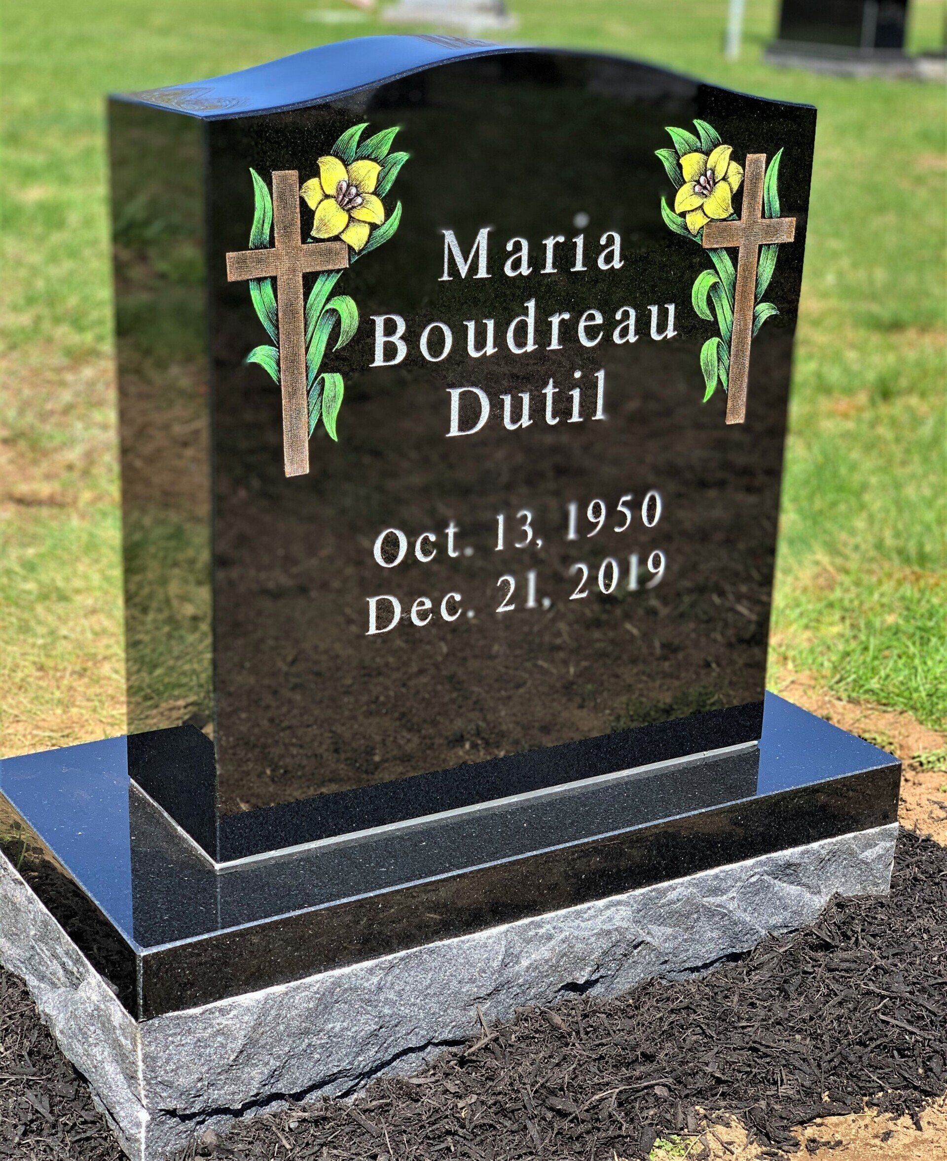 a black gravestone with flowers and crosses on it