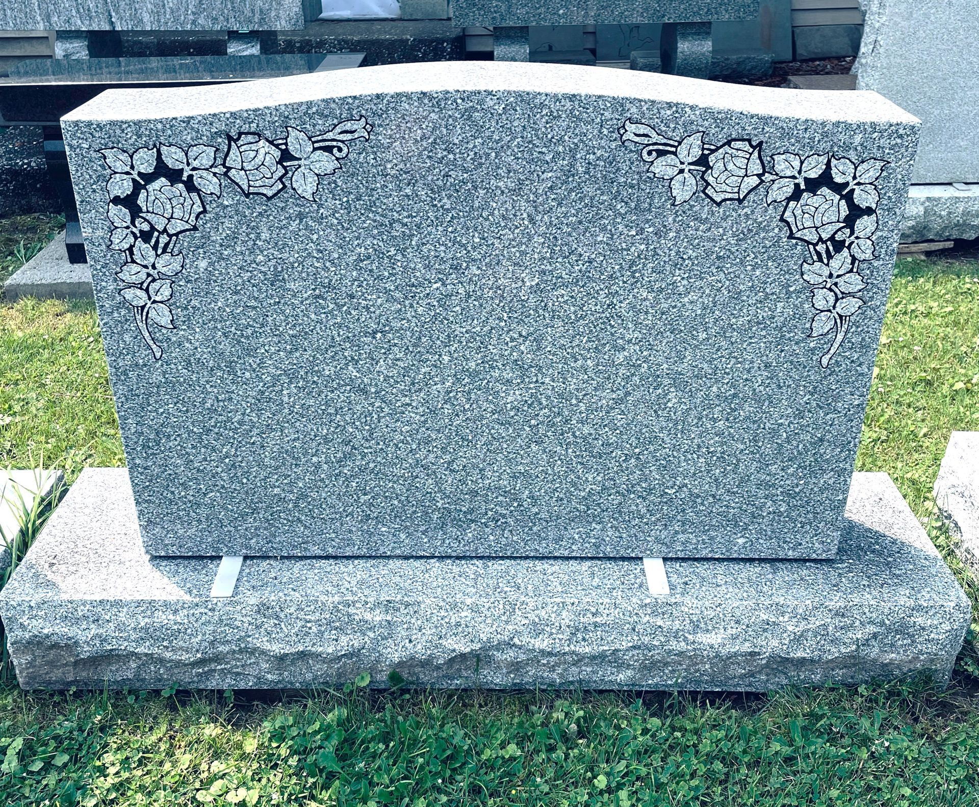 Grey granite headstone with floral carvings