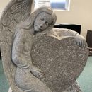 a granite monument in the shape of an angel holding a heart