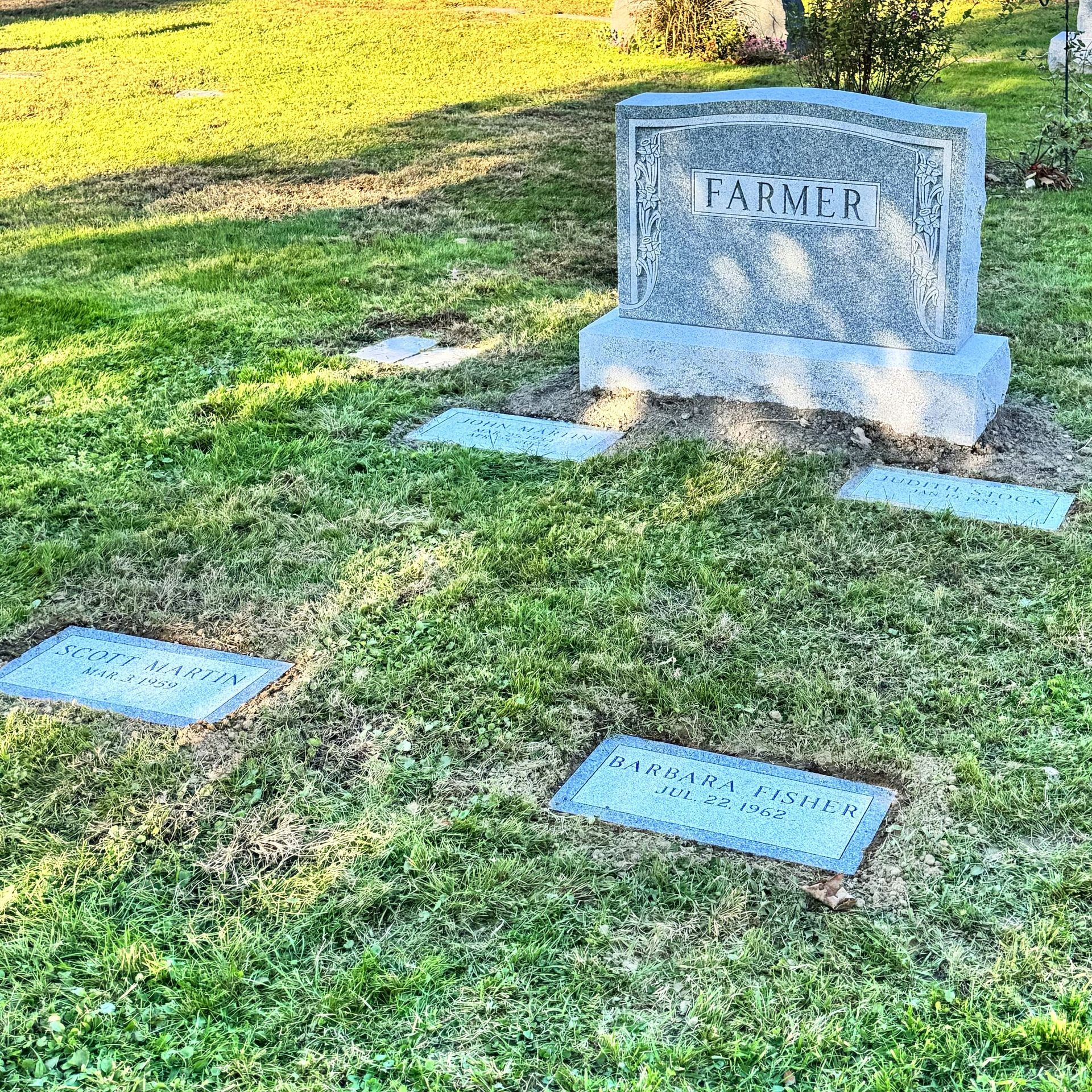 A Barre Grey Granite Headstone installed with matching footstones.