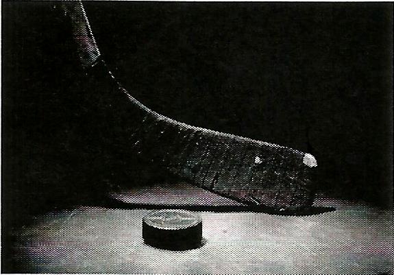 a hockey stick and puck are on a table in a dark room .