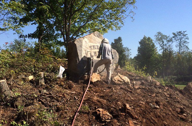 two men are working on a large rock in a field .
