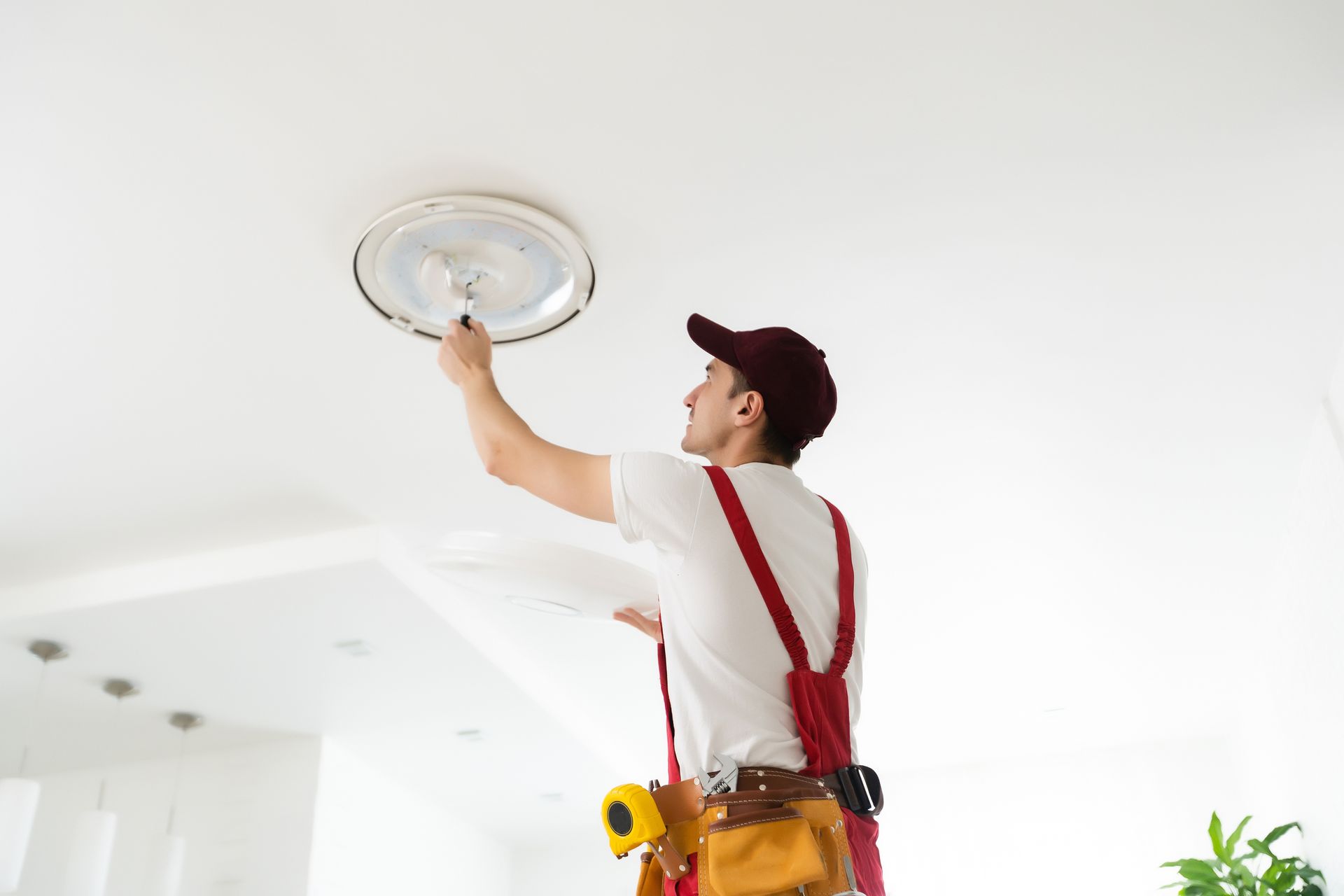 A man is fixing a light fixture on the ceiling.