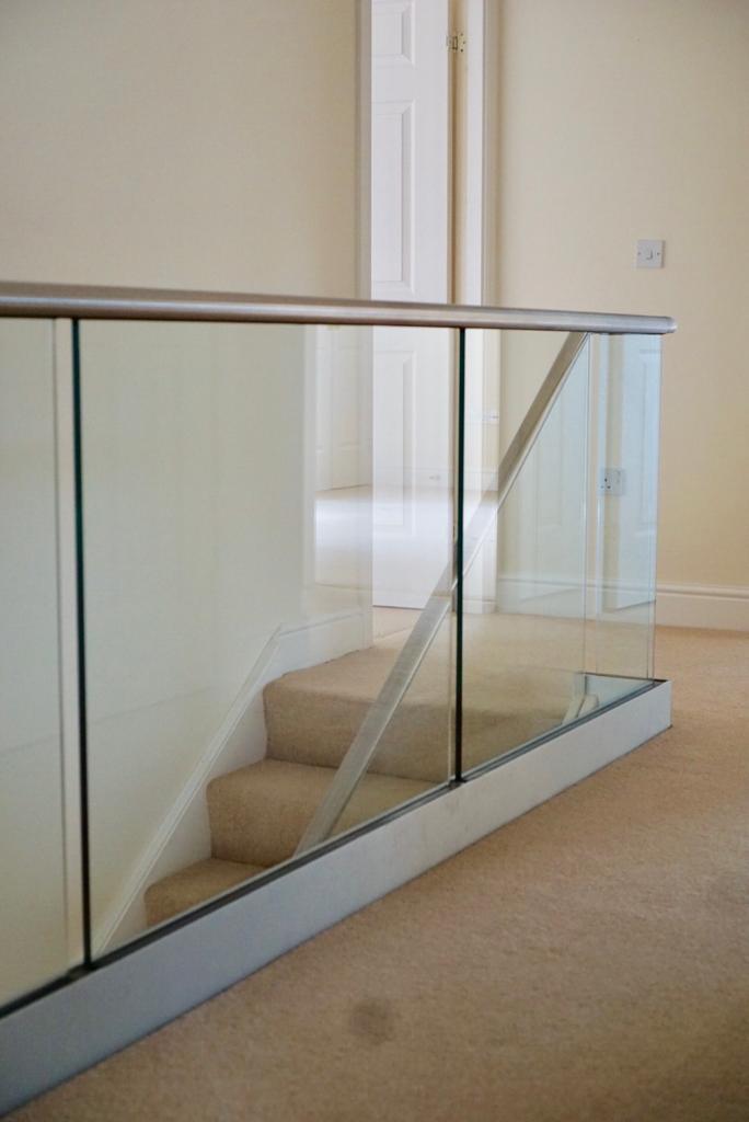 New glass balustrade with a bottom glazing channel and a stainless steel slotted handrail example 4