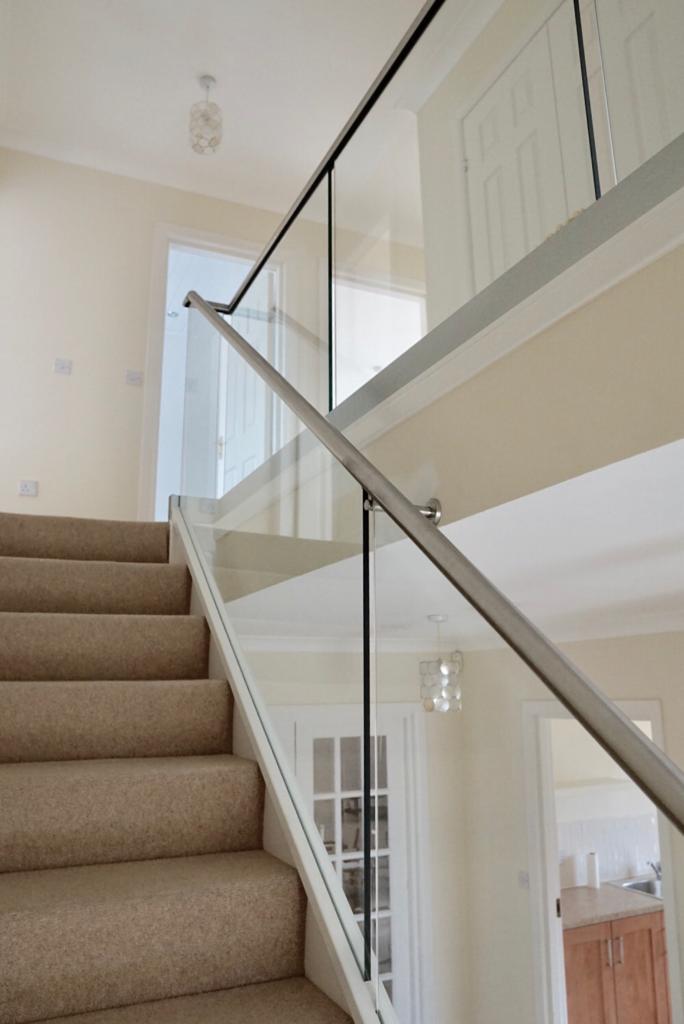 New glass balustrade with a bottom glazing channel and a stainless steel slotted handrail example 1