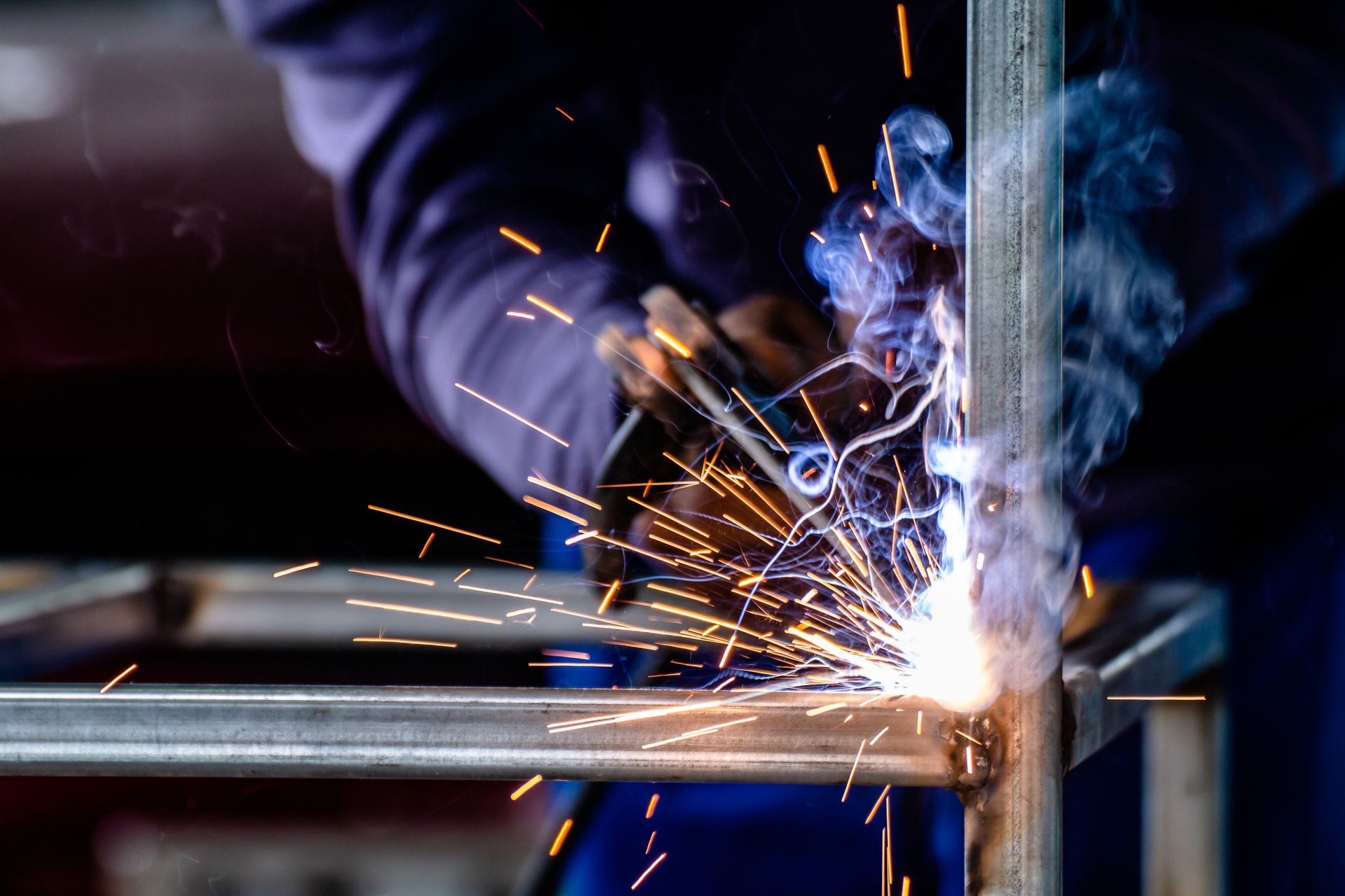 Welder in Protective Gloves Welding Metal Frame, Sparks and Smoke — Chris Horton Manufacturing in Bathurst, NSW