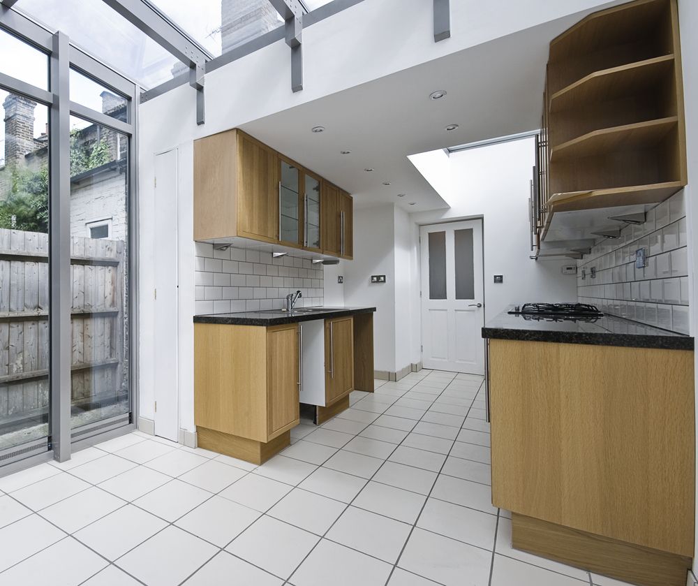 Modern Kitchen With Wooden Cabinets, White Tiled Floor, and Glass Roof — Barrington Coast Homes in Forster, NSW