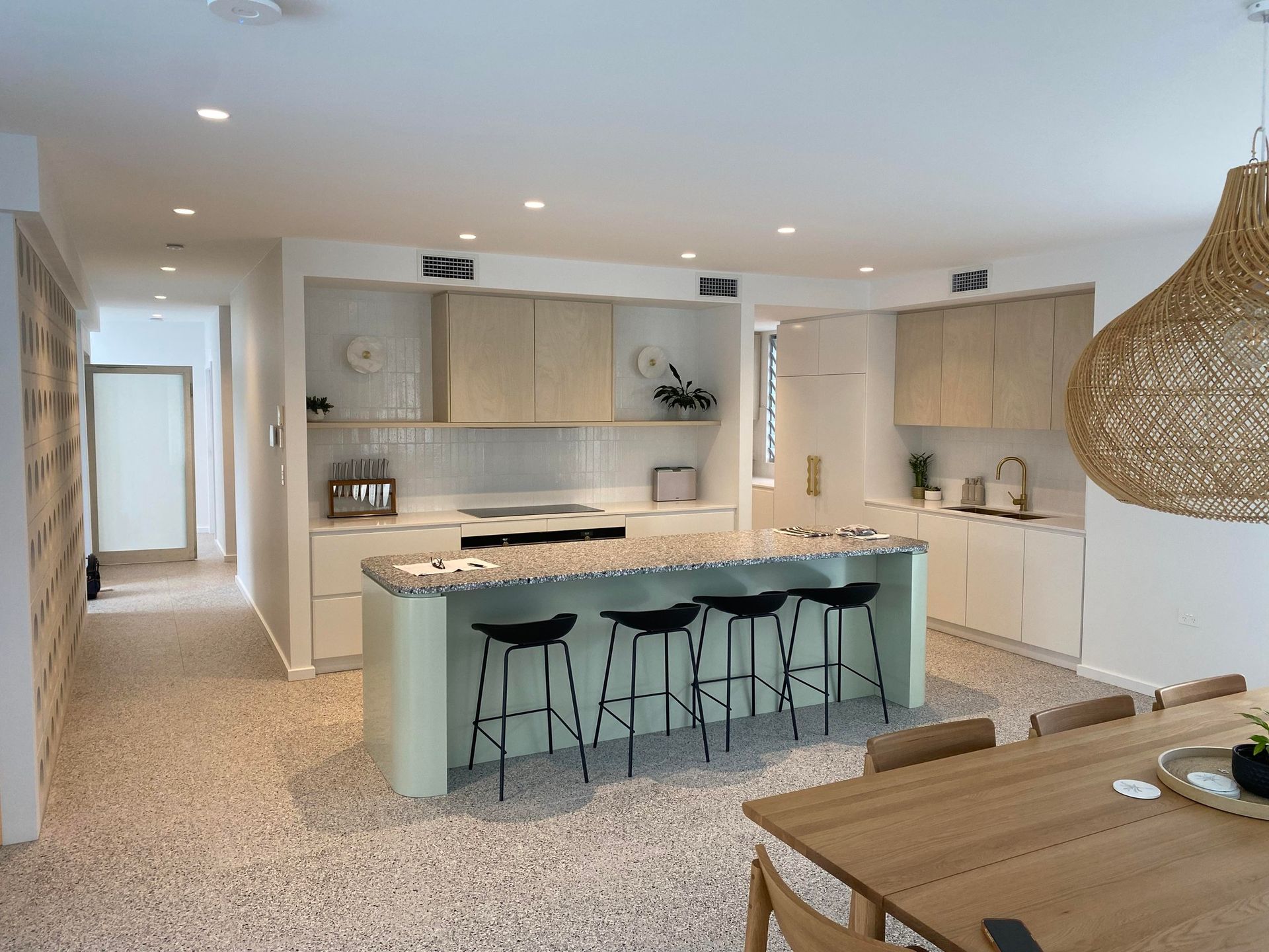 Modern kitchen with light green island, neutral cabinets, and terrazzo floors; dining area visible  — Barrington Coast Homes in Tallwoods, NSW