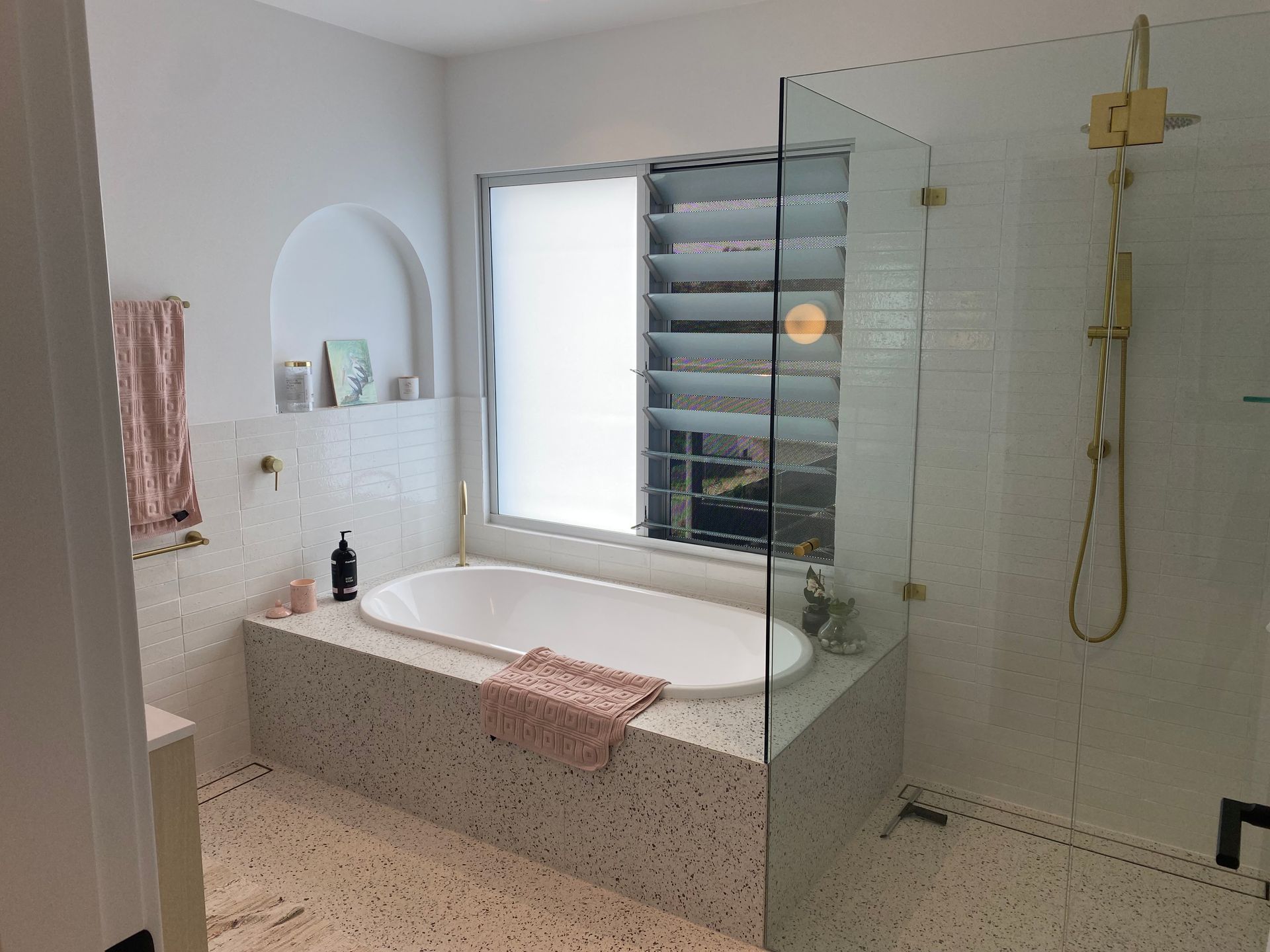 Modern bathroom with a bathtub, shower, and window; white, gold, and terrazzo tiles. — Barrington Coast Homes in Taree, NSW