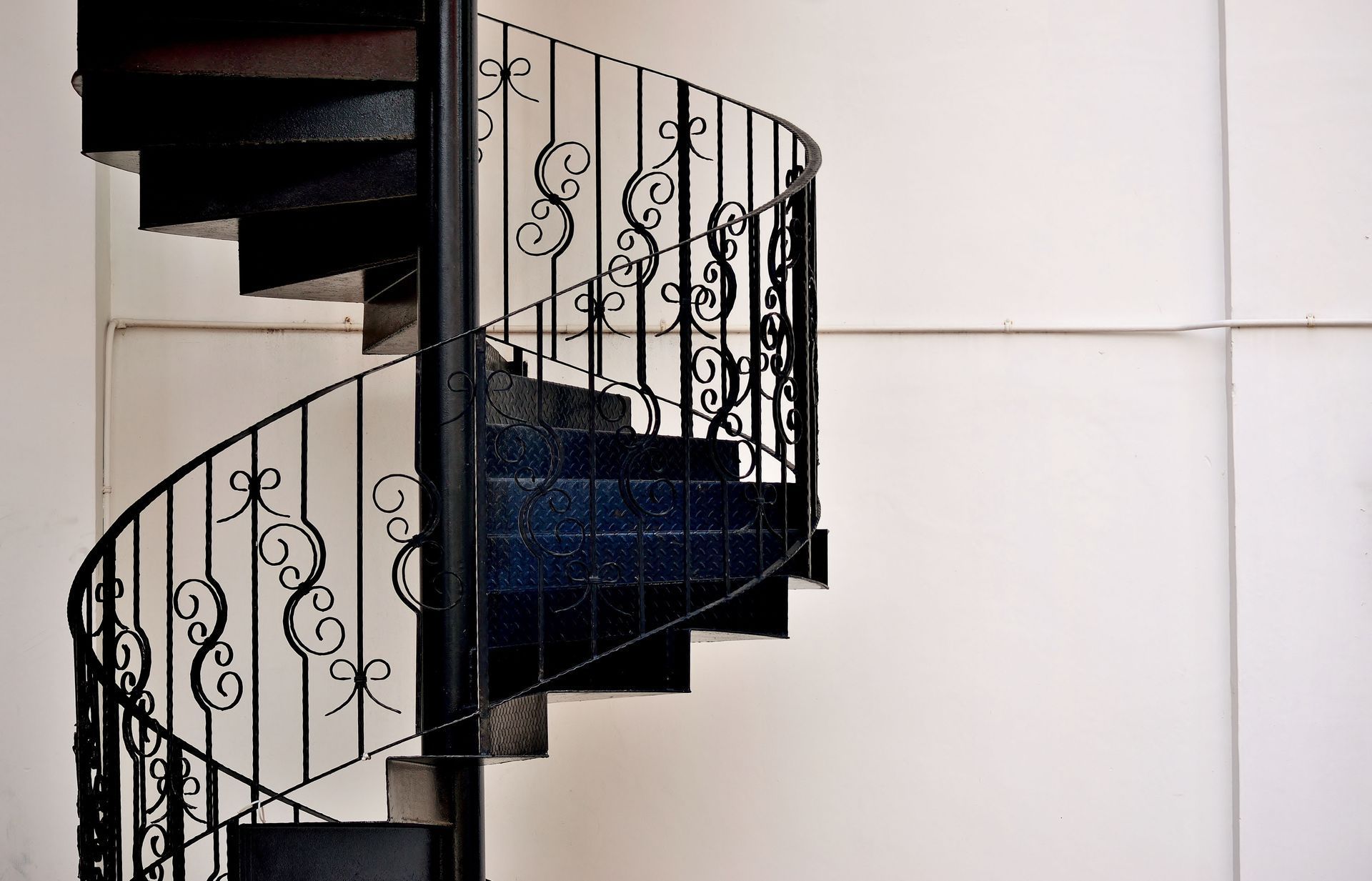 A black spiral staircase with a wrought iron railing