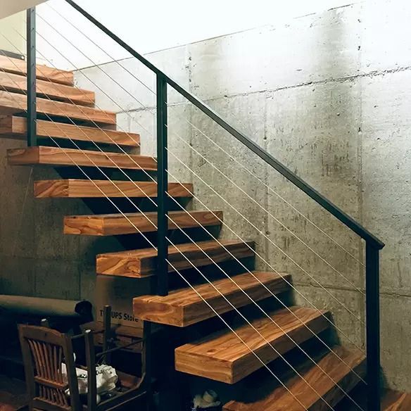 A wooden staircase with a metal railing and a chair