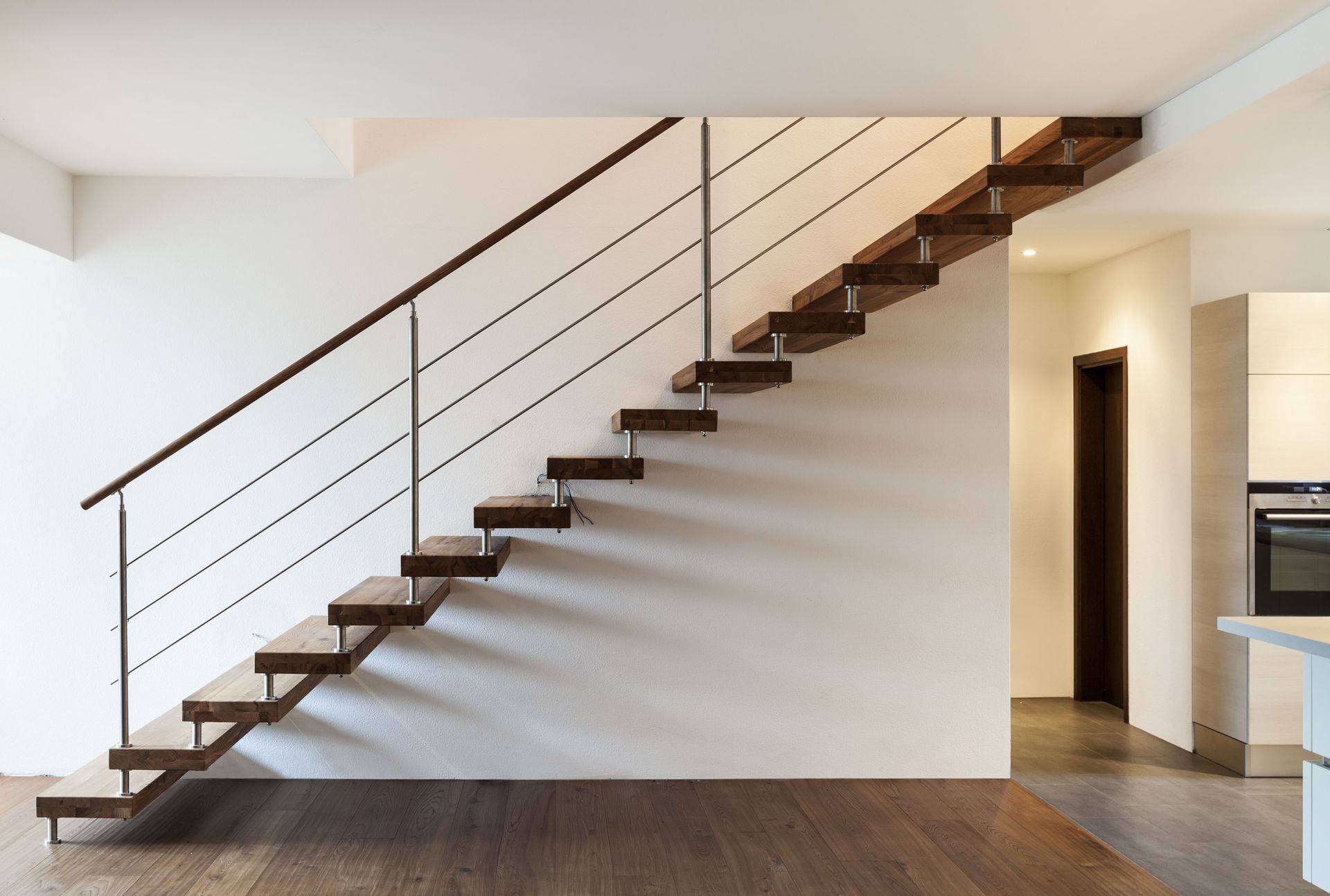 A wooden staircase with a metal railing in an empty room.