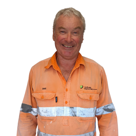 A man wearing an orange shirt and safety vest smiles for the camera