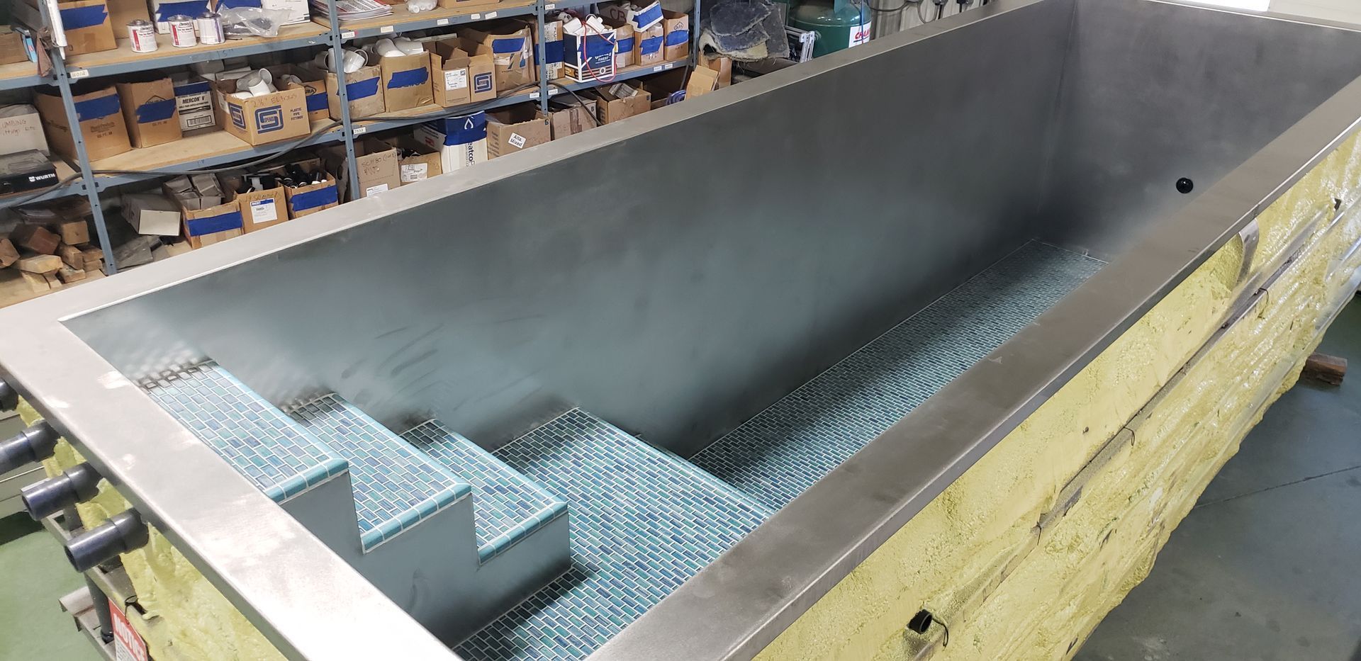 Inside view of a rectangular, metal-lined pool with steps, resting on yellow insulation.
