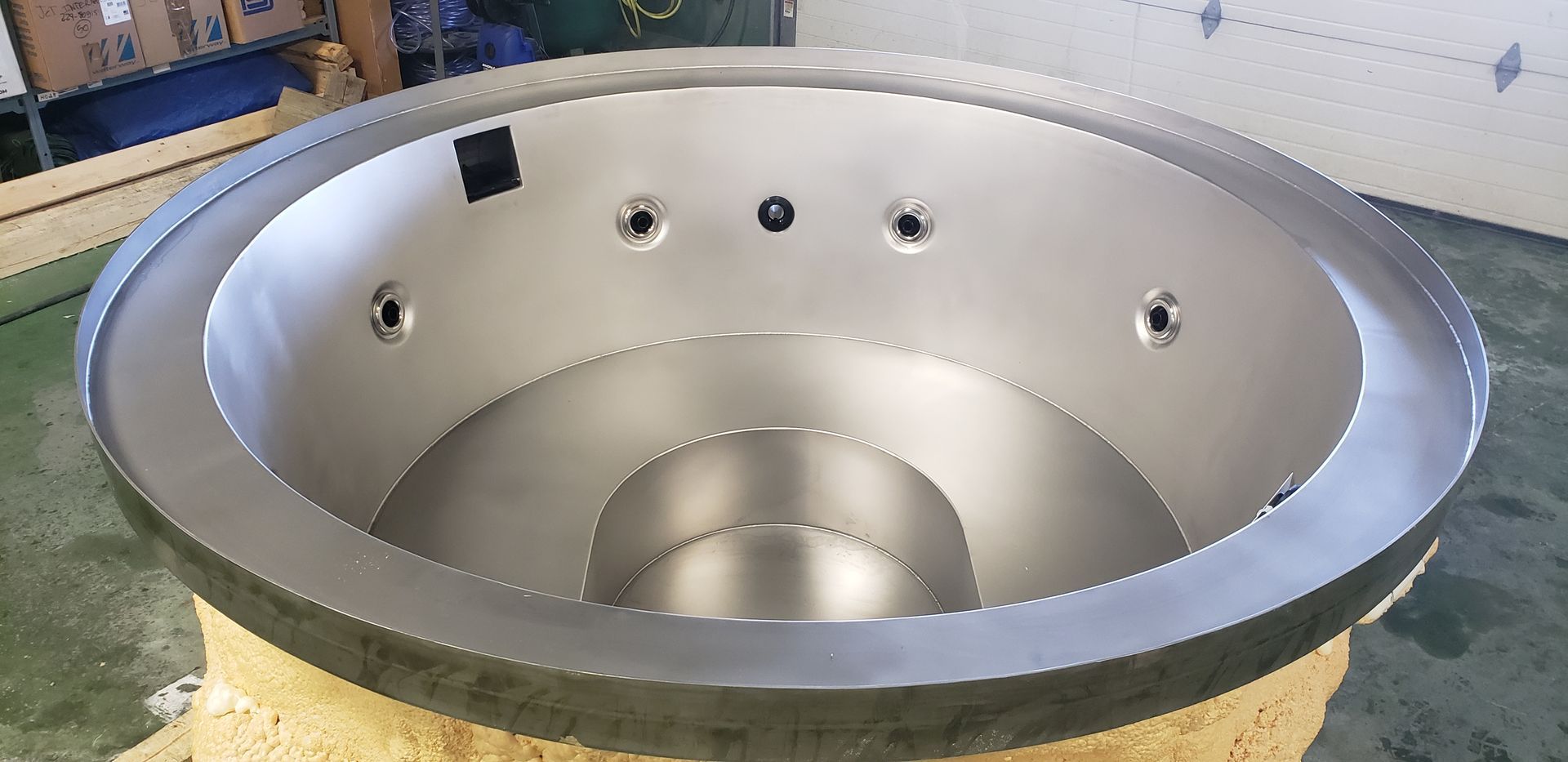 A stainless steel hot tub inside a workshop.