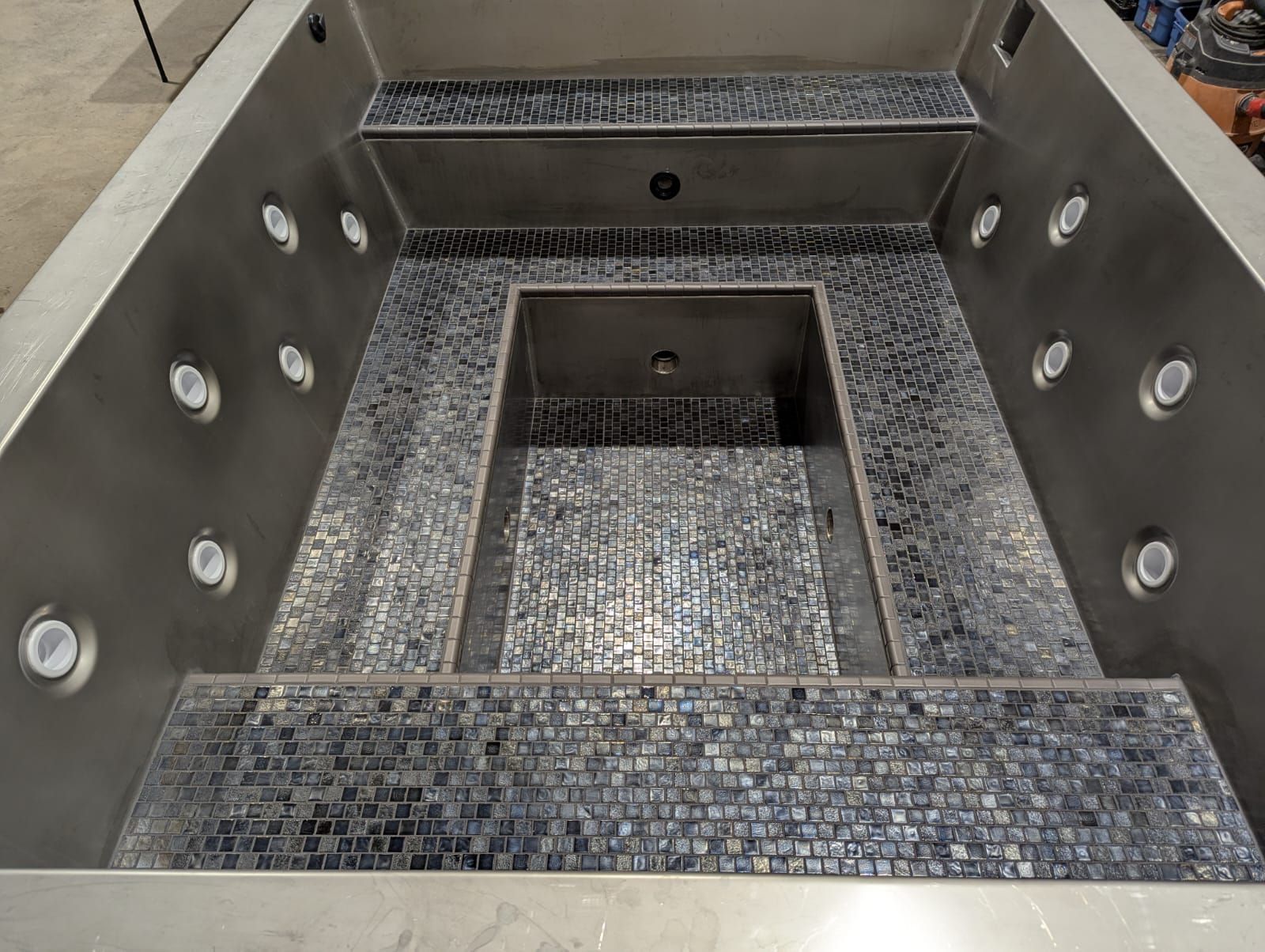 Inside view of a stainless steel and mosaic tile jacuzzi with jets.