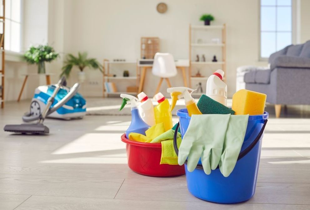 A living room filled with buckets of cleaning supplies and a vacuum cleaner.