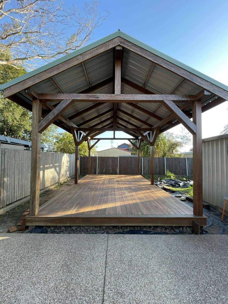 Wooden gazebo with a dark stained frame, deck, and corrugated metal roof in a yard. — Boundary Creek Timber in Wallaville, QLD