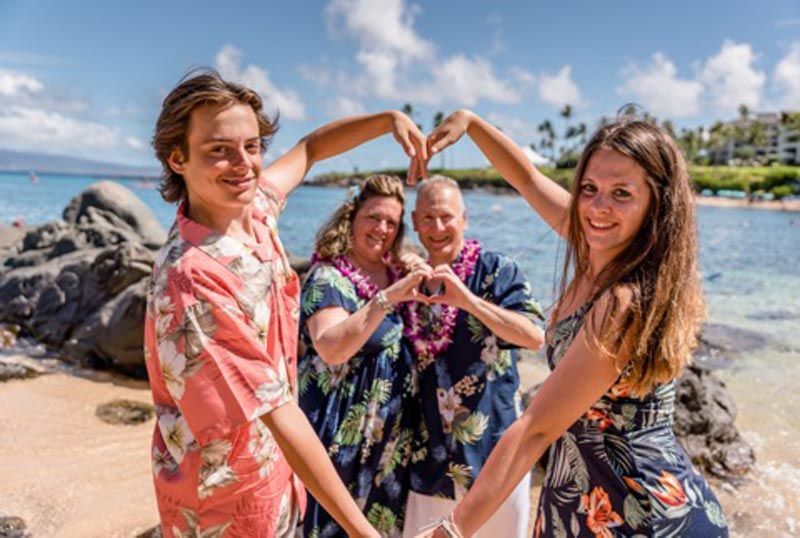 people on beach making arm hearts