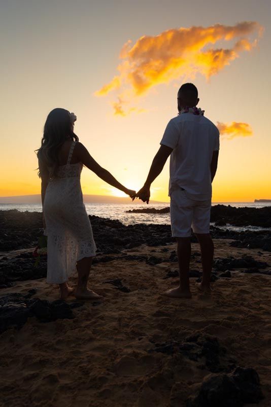 couple holding hands on beach at sunset