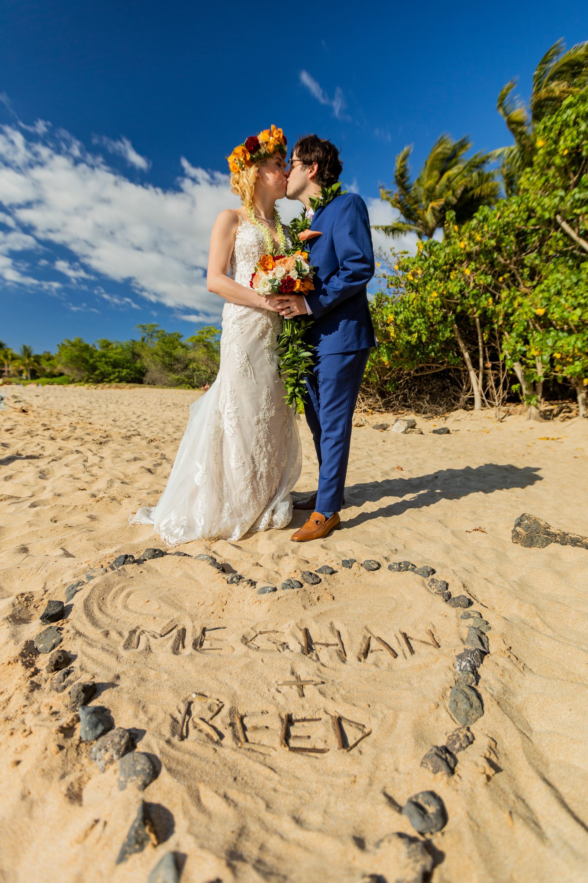 Couple kissing on beach; heart drawn in sand with names 