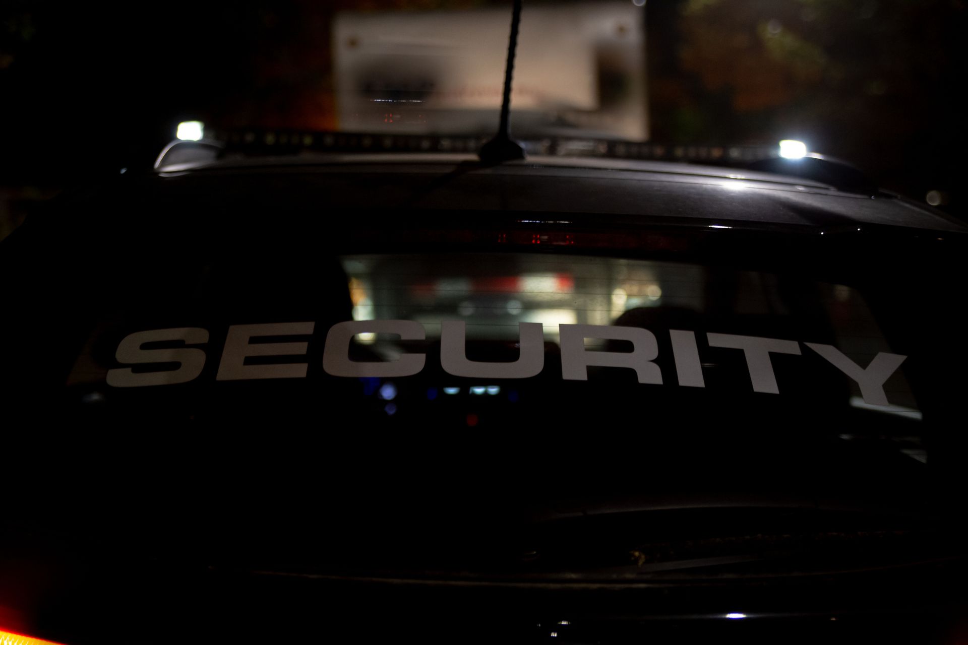 Black security vehicle at night with "SECURITY" on the back window.